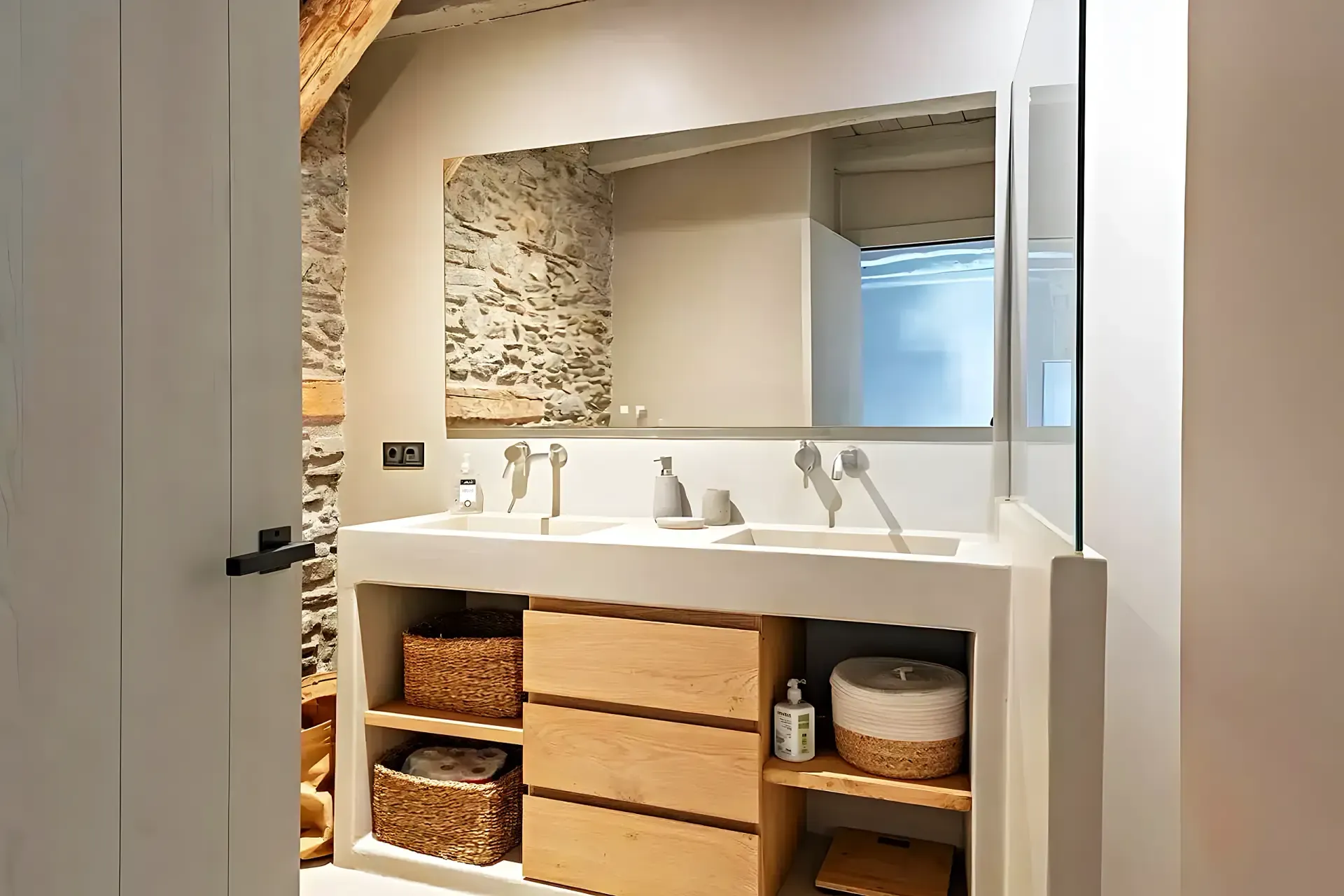 Salle de bain avec double vasque en béton ciré, tiroirs en chêne et mur en pierre apparente