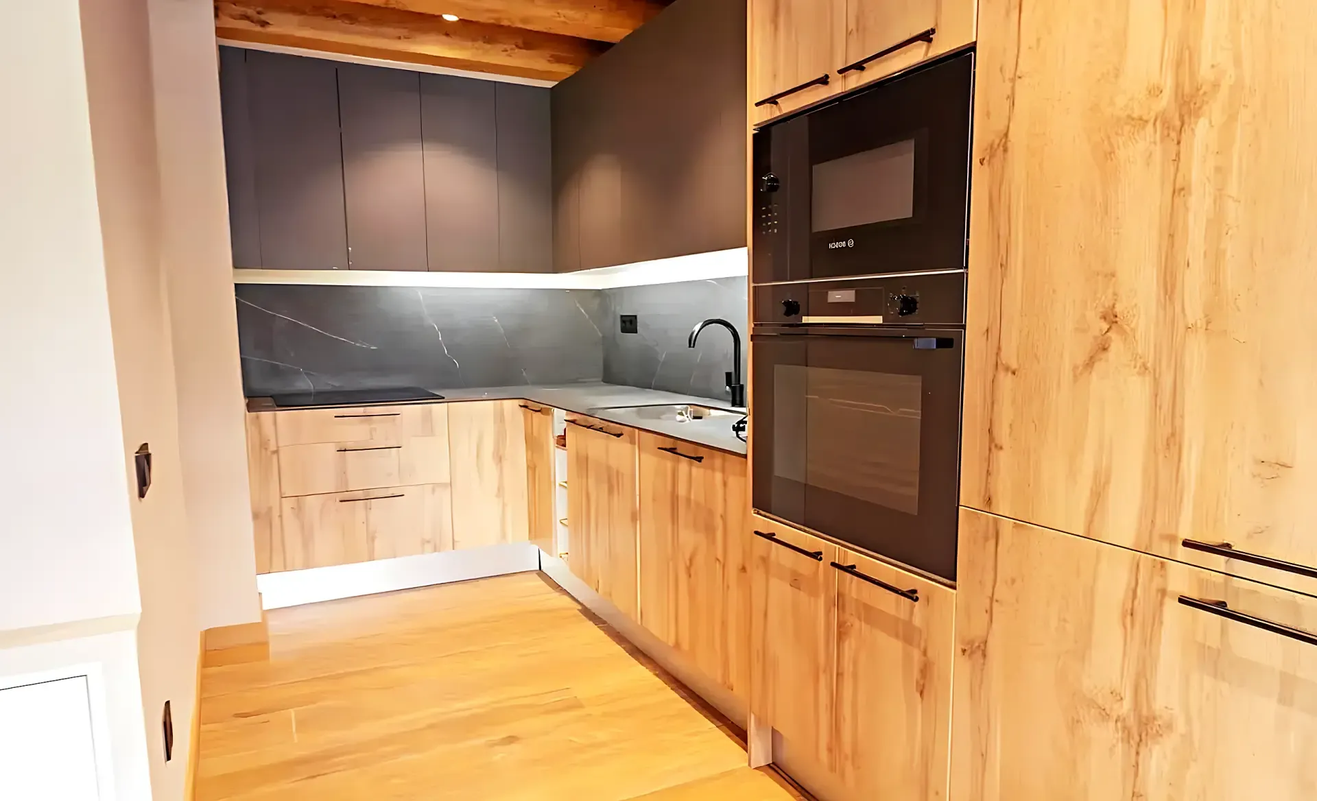 Cuisine en bois avec marbre noir, électroménager intégré et poutres apparentes