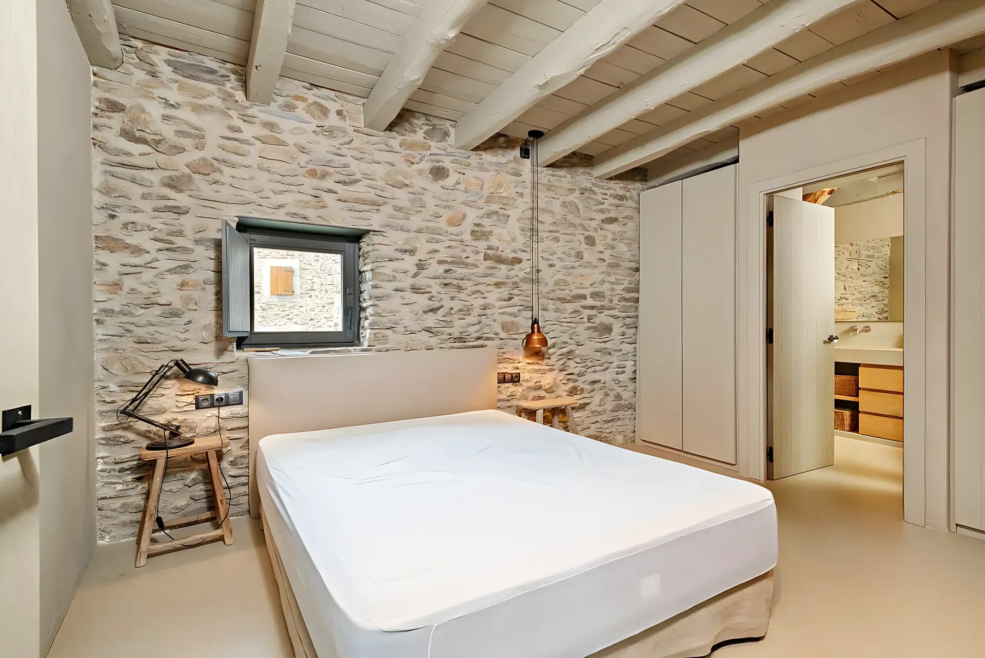 Dormitori amb paret de pedra vista d’una borda reformada